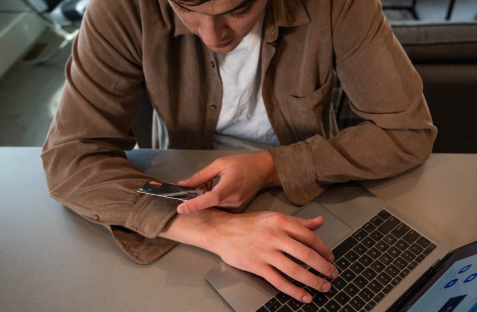 Fiatal férfi bankkártyával fizet egy laptopon