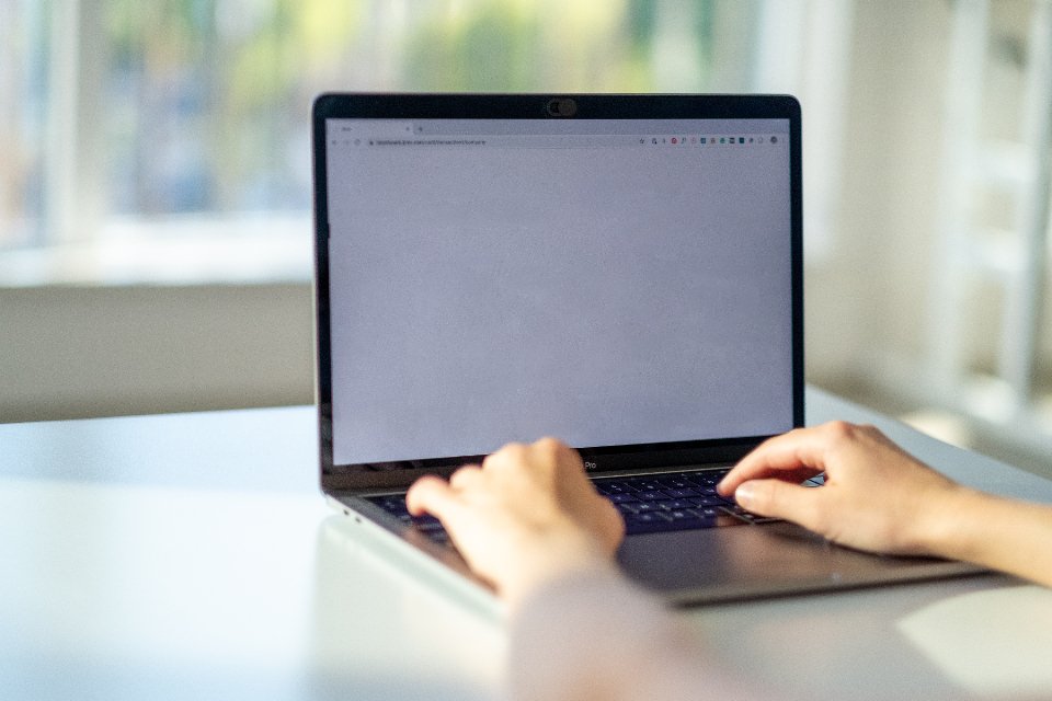 Kéz gépel egy laptop billentyűzetén egy világos irodában